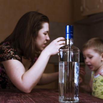 Matka s dítětem a lahví alkoholu