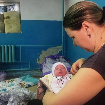 A woman holds her newborn baby as they take shelter in the basement of a perinatal centre in Kharkiv