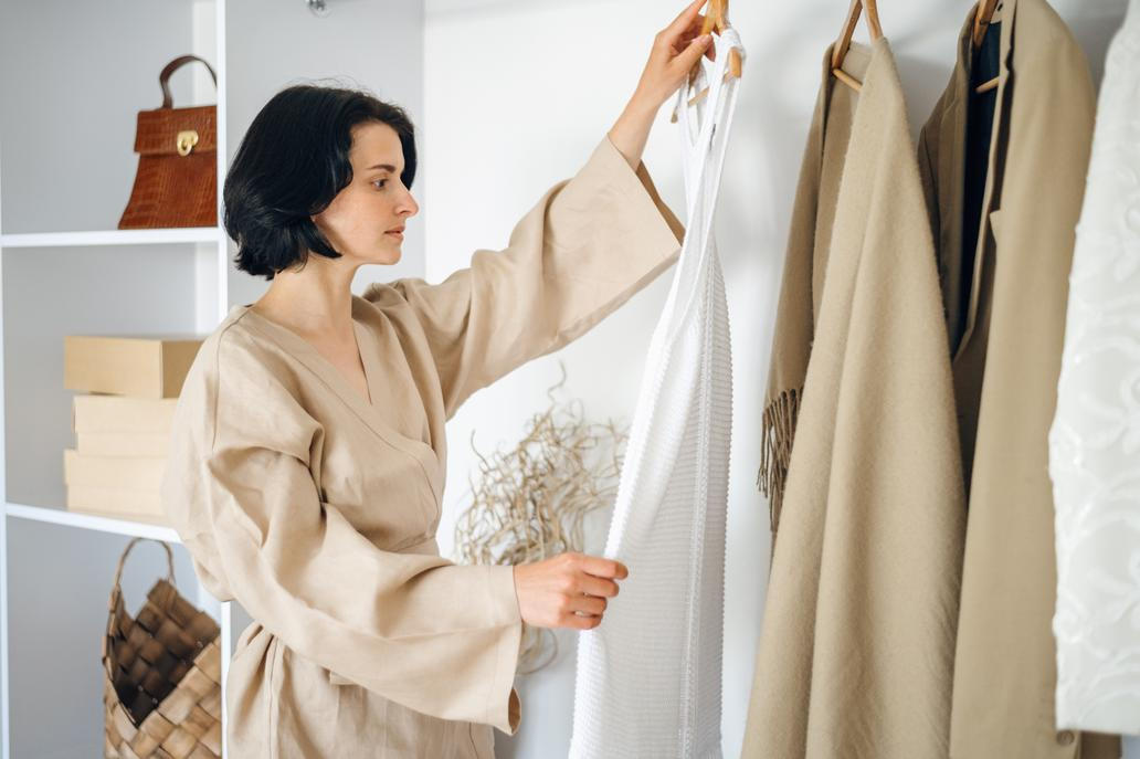 Žena v šatníku s neutrálníma barvama