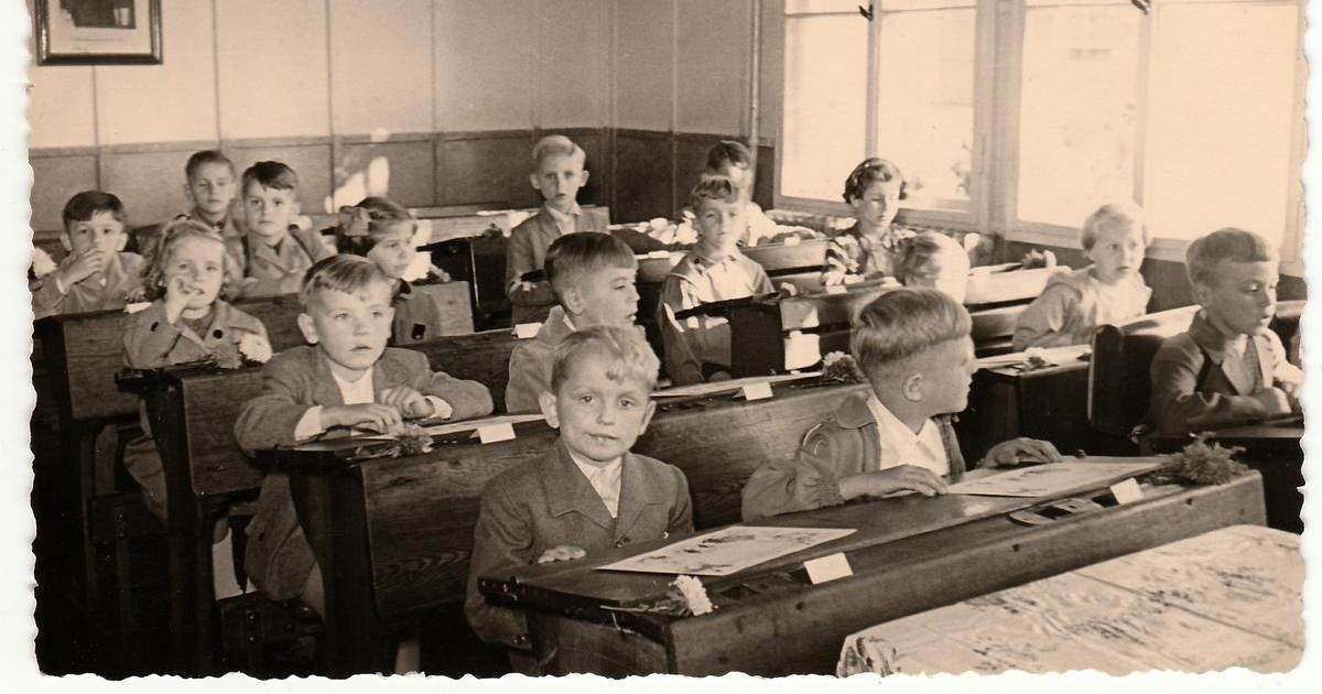 ČESKOSLOVENSKÁ SOCIALISTICKÁ REPUBLIKA – cca 50. léta: Retro fotografie zachycuje žáky sedící v dřevěných lavicích ve třídě. Dobový snímek skupiny spolužáků ve školní třídě.