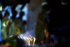 Křesťanská poutnice zapaluje svíčku uvnitř Chrámu narození Páně v Betlémě