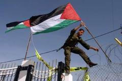 Palestinci vyvěšují vlajku u právě otevřeného přechodu v Rafáhu