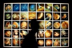 Silueta lékaře před plakátm ukazujícím vývoj lidstva