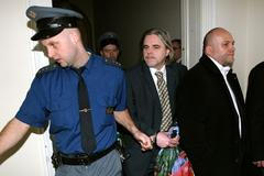 Eskorta přivádí Karla Srbu k soudu. Vpravo vedle stojí další obviněný, Karel Brei.