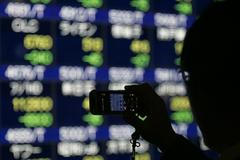 Muž si pořizuje fotografii panelu na burze v Tokiu