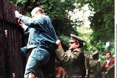 Občan NDR přelézá plot německé ambasády v Praze na podzim 1989