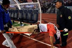 Zraněný fanoušek je odnášen na nosítkách při utkání Egypt - Alžírsko.