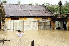 Vietnamec se brodí ke svému zaplavenému domu při tropické bouři Mirinae