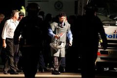 Policista v ochranném obleku opouští dům v Sydney.