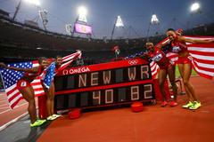 Americká štafeta na 4x100 metrů se usmívá u výsledkové tabule se svým světovým rekordem