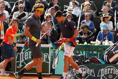 Roger Federer a Novak Djokovič se míjejí během semifinále French Open 2012