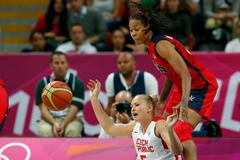 Česká basketbalistka Michaela Zrůstová sedí po pádu pod Američankou Seimone Augustusovou v utkání skupiny A na OH 2012 v Londýně.