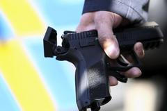 Policejní důstojník drží zbraň, kterou Pavel Vondrouš vystřelil na prezidenta Klause.