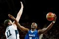 Francouzský basketbalista Ali Traore se snaží smečovat přes Američana Kevina Loveho v utkání základní skupiny A mezi USA a Francií na OH 2012 v Londýně.