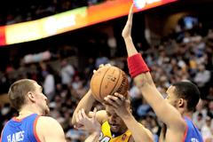 Andre Miller z Denveru se probíjí přes blok hráčů Philadelphie