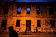 File photo of people walking next to a destroyed building in Mostar