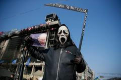 Participant hold a sign depicting Russian President Vladimir Putin as he attends an anti-war rally at Independence Square in Kiev