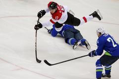 Austria's Michael Raffl flies through the air after tripping over Slovenia's Ziga Pavlin during the second period of their men's ice hockey playoffs qualification game at the 2014 Sochi Winter Olympic