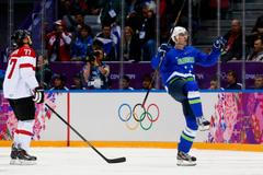 Slovenia's Kovacevic celebrates his goal as Austria's Lebler reacts during second period of their men's ice hockey playoffs qualification game at 2014 Sochi Winter Olympics
