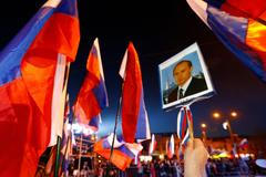 A woman holds a portrait of Russia's President Vladimir Putin during celebrations on the main square of the Crimean city of Simferopol