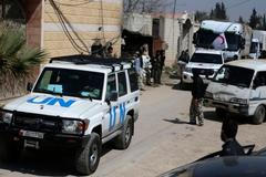 Free Syrian Army fighters escort a convoy of vehicles and trucks carrying humanitarian supplies in the Duma neighbourhood of Damascus