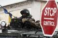 An armed man, believed to be Russian serviceman, stands guard outside a Ukrainian military base in Perevalnoye