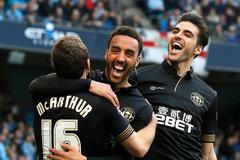 Wigan Athletic's Perch celebrates with teammates McArthur and Gomez after scoring a goal against Manchester City during their English FA Cup quarter final match in Manchester