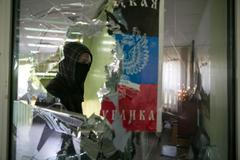 Proruský separatista prochází kolem rozbitého okna na radnici v Mariupolu.