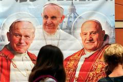 Papežové Jan Pavel II., František  a Jan XXIII. na plakátu v obchodě v Římě