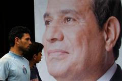 People walk past a poster of presidential candidate Abdel Fattah al-Sisi at one of his campaign headquarters in Cairo