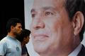 People walk past a poster of presidential candidate Abdel Fattah al-Sisi at one of his campaign headquarters in Cairo