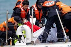 South Korean coastguard officers recover a body on their vessel at the site where the capsized passenger ship Sewol sank in the sea off Jindo