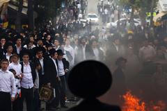 Ultra-Orthodox Jewish men and youths stand next to a fire during a protest in Jerusalem's Mea Shearim neighbourhood