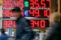 People pass by a board displaying exchange currency rates in Moscow