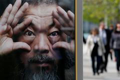 People walk beside an advertising poster for the exhibition 'Evidence' by Chinese artist Ai Weiwei at the Martin-Gropius Bau in Berlin