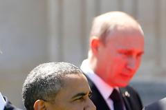 Red light reflected from the carpet illuminates Russian President Vladimir Putin in Benouville