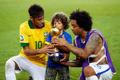 Brazil's Marcelo helps his son hold the trophy as teammate N