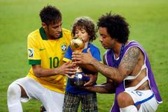 Brazil's Marcelo helps his son hold the trophy as teammate N