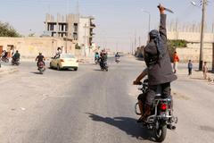 Man holds up a knife as he rides on the back of a motorcycle touring the streets of Tabqa city with others in celebration after Islamic State militants took over Tabqa air base, in nearby Raqqa city