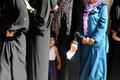 A homeless Palestinian boy stands in line with his mother as they wait to receive aid at a United Nations-run school where they are taking refuge in Khan Younis