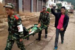 Policisté nesou zraněné dítě po zemětřesení v regionu Ludian