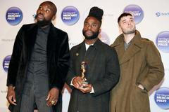 Young Fathers pose with their trophy after winning the 2014 Mercury Prize in London