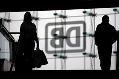Commuters walk in front of the logo of German rail operator Deutsche Bahn at Berlin's Hauptbahnhof main railway station in Berlin