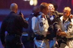 Záchranáři vynášejí z kavárny zraněnou ženu.