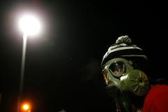 Protestující s plynovou maskou během shromáždění za Michala Browna před policijním oddělením ve Fergusnu