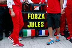 Sign in support of Marussia Formula One driver Jules Bianchi of France is seen among members of Ferrari Formula One team before the first Russian Grand Prix in Sochi