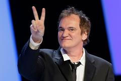 US director Quentin Tarantino flashes a victory sign as he arrives on the stage during the 39th Cesar Awards ceremony in Paris