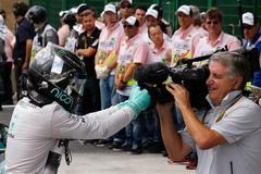 Mercedes Formula One driver Nico Rosberg of Germany jokes with the cameraman to celebrate as he steps out of his car after winning the Brazilian Grand Prix in Sao Paulo