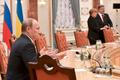 Vladimir Putin na jednání v Minsku (v pozadí Angela Merkelová a Petro Porošenko)