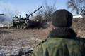 A man watches a tank of the separatist self-proclaimed Donetsk People's Republic Army manoeuvre near a checkpoint on the road from Vuhlehirsk to Debaltseve
